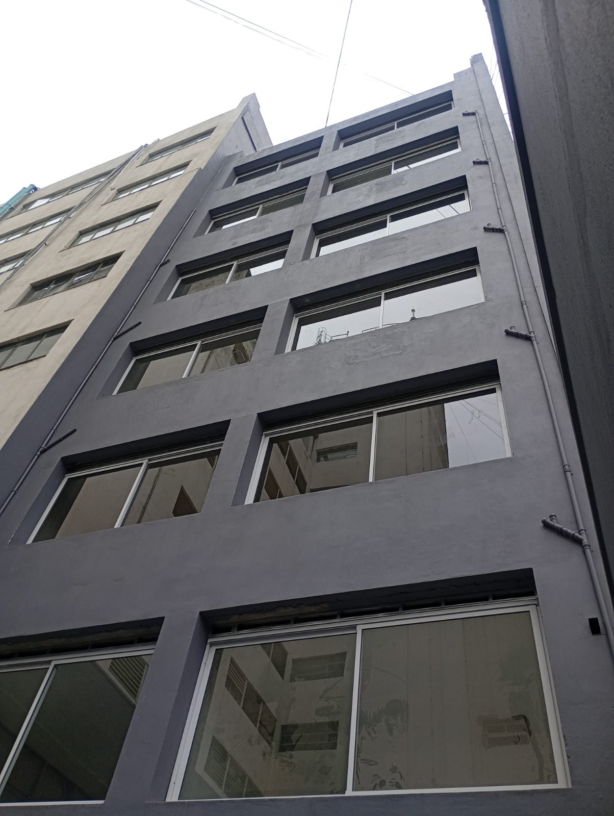 Fachada gris de un edificio con ventanas corredizas en todos los pisos
