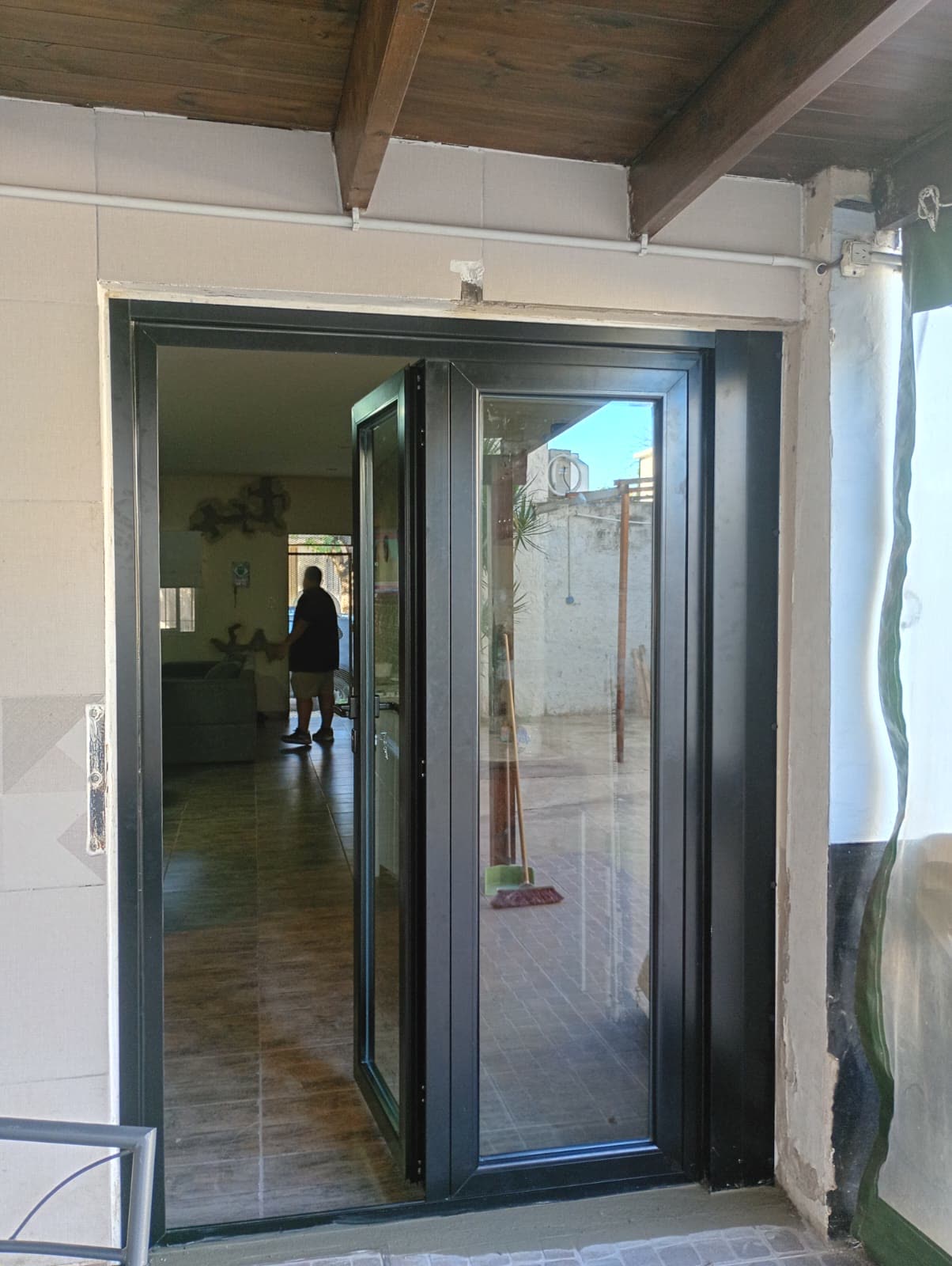 Puerta de aluminio negra de dos hojas hacia un patio